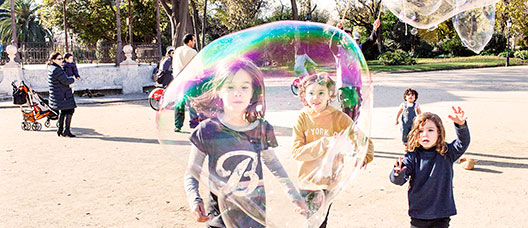 Foto: P. de Grenet Grup de nens i nenes corrent pel parc de la Ciutadella seguint una bombolla de sabó